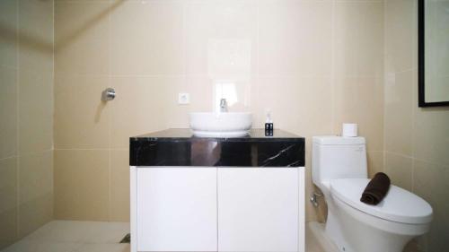 a bathroom with a sink and a toilet at Simple and Clean 2BR at Grand Sungkono Lagoon Apartment By Travelio in Surabaya