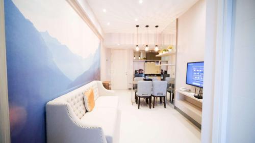 a living room with a couch and a dining room at Clean and Comfort Living 2BR at Anderson Supermall Mansion Apartment By Travelio in Surabaya