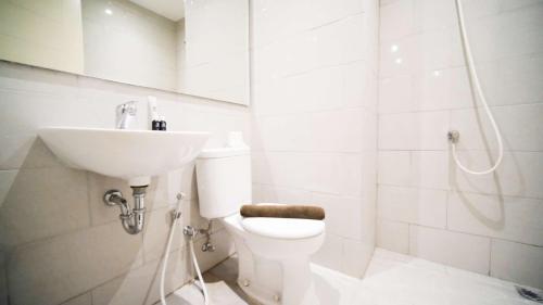 a white bathroom with a sink and a toilet at Clean and Comfort Living 2BR at Anderson Supermall Mansion Apartment By Travelio in Surabaya