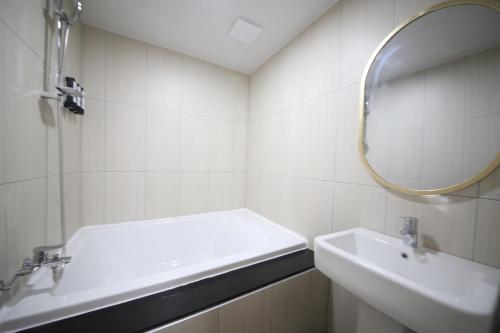 a white bathroom with a sink and a mirror at Calm Rest Hotel Masan in Changwon