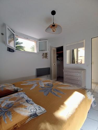 une chambre avec un grand lit et deux fenêtres dans l'établissement Le gîte des Palmiers, à Hyères