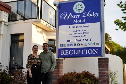 a man and a woman standing in front of a sign at Ulster Lodge Motel in Hamilton