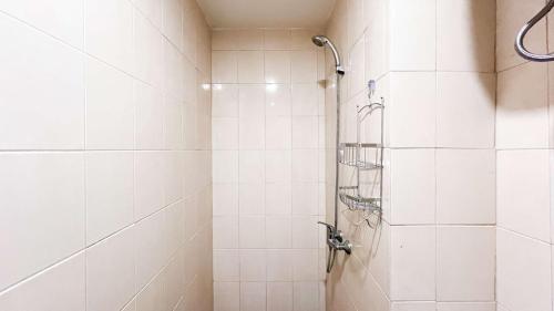 a bathroom with a shower with white tiles at Comfort Studio Apartment Vida View Makassar By Travelio in Pampang