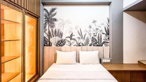 a bedroom with a bed with a tropical print on the wall at Comfort Studio Apartment Vida View Makassar By Travelio in Pampang