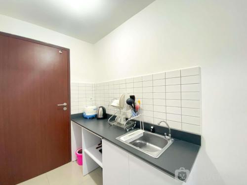 a kitchen counter with a sink and a brown door at Restful and Tidy Studio Sayana Bekasi Apartment By Travelio in Bekasi