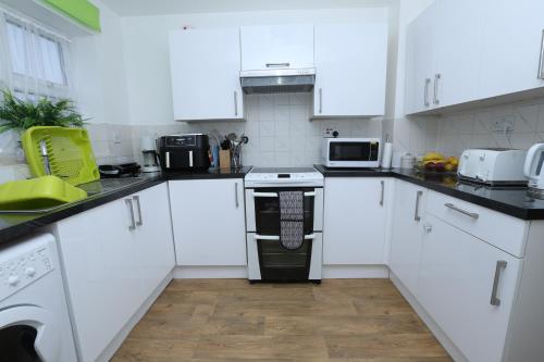 a kitchen with white cabinets and a black and white oven at BEAUTIFUL 4 BED HOUSE IN Cul-De-Sac in Erith