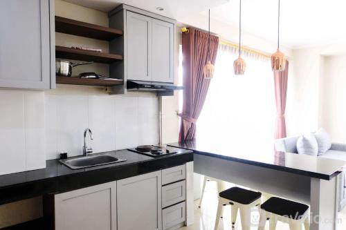 a kitchen with white cabinets and a black counter top at Spacious 3BR at Gateway Pasteur Apartment By Travelio in Bandung