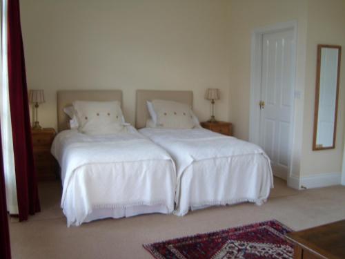 a bedroom with two beds with white sheets and a mirror at The Hall Farm Bed And Breakfast in Tilbrook