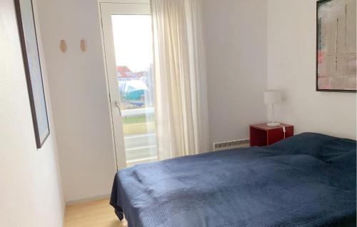 a bedroom with a blue bed and a window at Apartment Skudehavnen in Rudkøbing