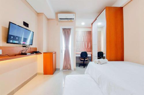 タンゲランにあるNice and Simply Look Studio Apartment at B Residence By Travelioのベッドとテレビがあるホテルの部屋