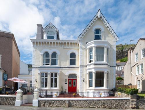a white house with a red door at The Stella Historic Llandudno Bed & Breakfast in Llandudno
