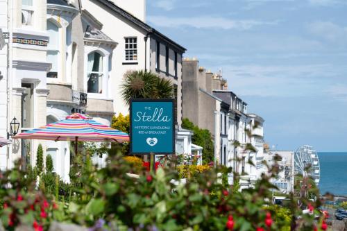a sign on a street with buildings and an umbrella at The Stella Historic Llandudno Bed & Breakfast in Llandudno