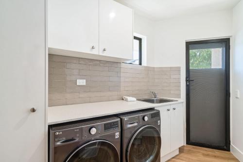 a kitchen with a washing machine and a sink at Tranquil Tides Retreat - Coastal Waterfront Escape in Caloundra