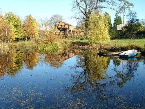 a boat on a lake with a house in the background at The Hall Farm Bed And Breakfast in Tilbrook
