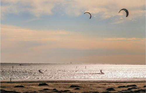 two people flying kites in the water at the beach at 2 Bedroom Cozy Apartment In Grado in Grado