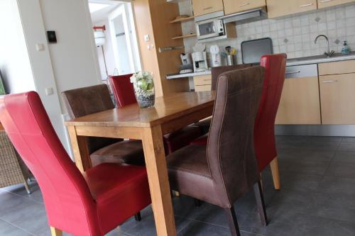 une cuisine avec une table en bois et des chaises rouges dans l'établissement Ferienhaus "Buurtweg 219" mit Schwimmbad, à Stavenisse