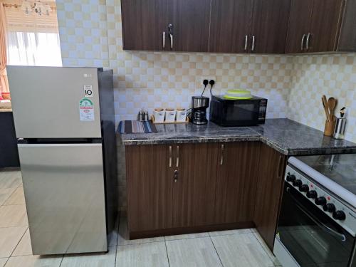 a kitchen with a refrigerator and a counter top at Fully furnished 3 bedroom apartment in Mirembe Villas Kigo, Uganda in Kigo