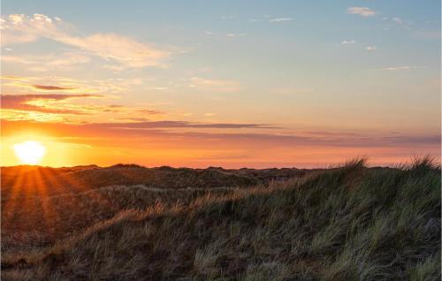 a sunset on top of a hill with grass at Amazing Home In Hvide Sande With Sauna in Bjerregård