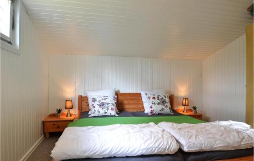 a bedroom with a large bed in a room with white walls at Amazing Home In Hvide Sande With Sauna in Bjerregård