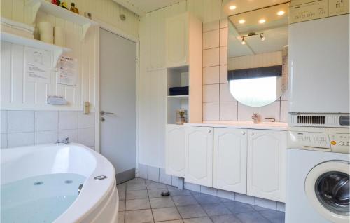 a bathroom with a tub and a washing machine at Amazing Home In Hvide Sande With Sauna in Bjerregård