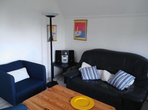 a living room with a black couch and a coffee table at Gemütliches Ferienhaus mit Garten und einer Terrasse mit Windfang in Anjum