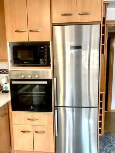a kitchen with a stainless steel refrigerator and a microwave at NUEVO Con piscina a 2 minutos estación tren AVE in Zaragoza