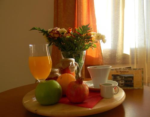 a table with a plate of fruit and a glass of orange juice at Agnantio in Ioannina