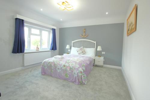a bedroom with a bed with a purple bedspread and a window at Deluxe 3 Bedroom 2 Bath House &Parking by CozyNest in Reading