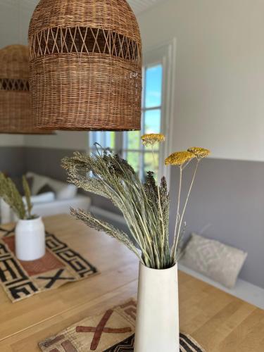 un vase avec des fleurs sur une table et une lampe dans l'établissement Oyat, à Saint-Hilaire-de-Riez