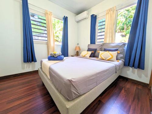 a bedroom with a large bed with blue curtains at Erima Lodge 1 in Arue