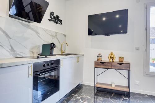 a kitchen with a stove and a tv on the wall at Studio 1 in Coubron