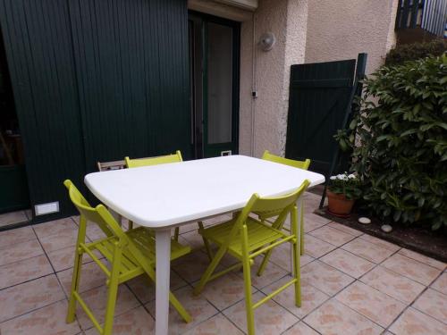 une table blanche et quatre chaises sur la terrasse dans l'établissement Appartement avec jardinet et terrasse, à Saint-Jean-de-Luz