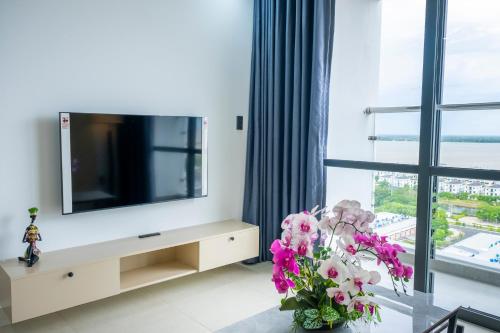 a living room with a flat screen tv and flowers at Sophia Apartment - Sophia Center Phu Cuong in Ấp Rạch Mẹo