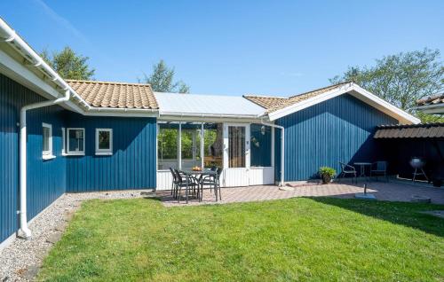a blue shed with a table and chairs in a yard at Nice Home In Skælskør With Sauna in Skælskør