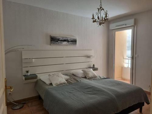 a bedroom with a bed and a chandelier at Appartement génial en centre ville avec parking in Cavalaire-sur-Mer