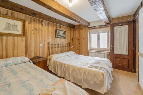 zwei Betten in einem Zimmer mit Holzwänden in der Unterkunft El Rincon De La Morena in Montemayor de Pililla