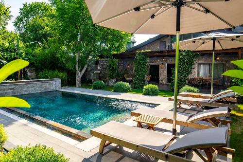 a pool with chairs and umbrellas next to a house at Kaya Villas Exclusive in Kayakoy