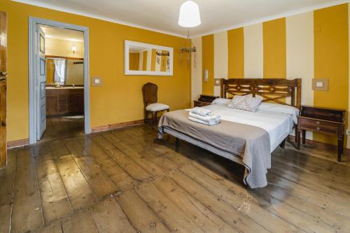 a bedroom with a bed with yellow walls and wooden floors at Laguna Herrera in Campo de Cuéllar