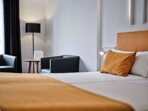 a hotel room with a bed and two chairs at Hotel Lux Santiago in Santiago de Compostela