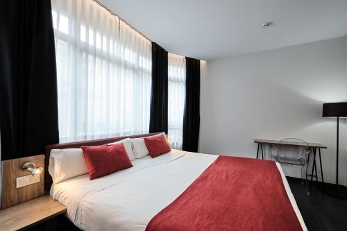 a bedroom with a bed with red pillows and a window at Hotel Lux Santiago in Santiago de Compostela
