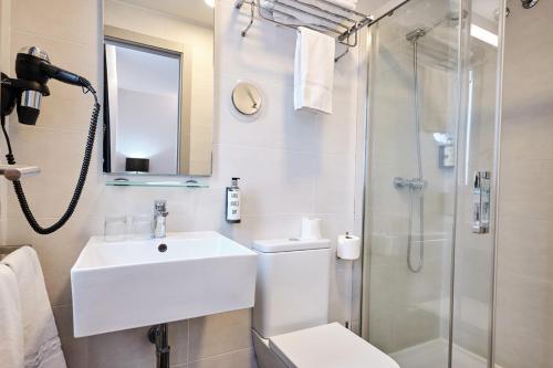 a white bathroom with a sink and a shower at Hotel Lux Santiago in Santiago de Compostela