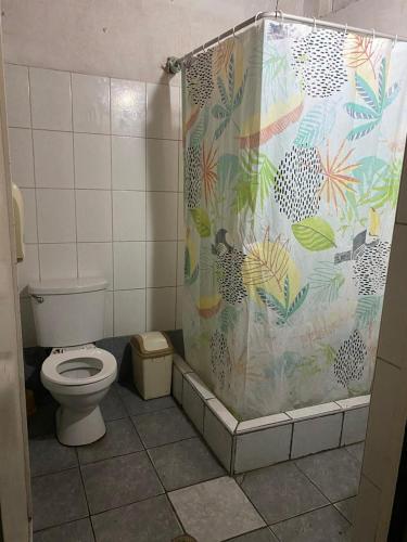 a bathroom with a toilet and a shower curtain at Enkanta Guest House in Trujillo