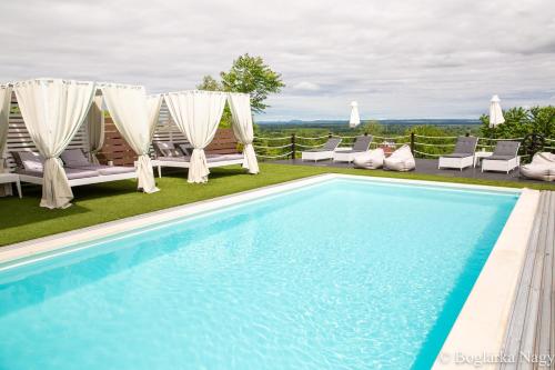a swimming pool with chaises and chairs next to at Love and Dream Élményvilla in Zalakaros