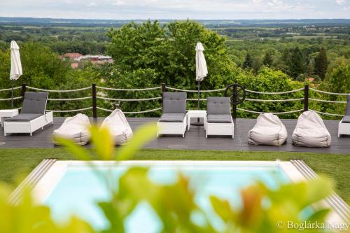 a pool with chairs and umbrellas on a patio at Love and Dream Élményvilla in Zalakaros