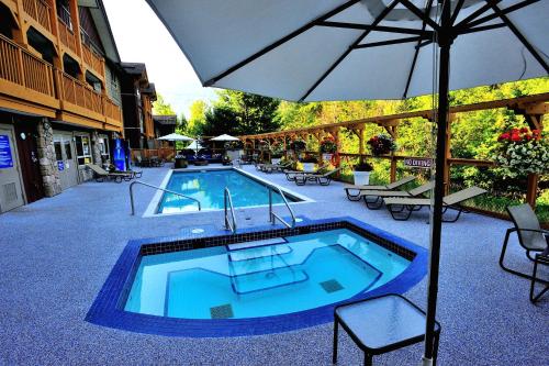 a swimming pool with an umbrella and tables and chairs at Pemberton Valley Lodge in Pemberton