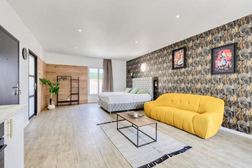a living room with a yellow couch and a bed at Studio 1 in Coubron