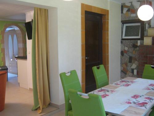 a dining room with a table and green chairs at Gemütlicher Ferienbungalow mit eigenem Ruderboot in Crivitz