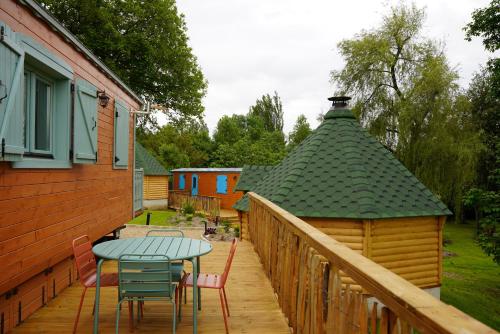 a deck with a table and chairs and a building at Roulottes et son kota grill sauna in Bucilly