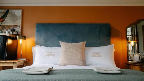 a bedroom with a bed with a blue headboard and white pillows at Sonnekus Boutique Hotel & Bistro in Kalk Bay