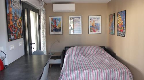 Cette chambre comprend un lit, une table et des photos sur le mur. dans l'établissement Entre Banyuls et Collioure T2 à Port vendres, à Port-Vendres